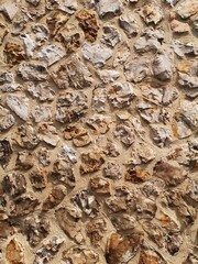 A masonry wall af sandcolored boulders. Seen up close. Detail.