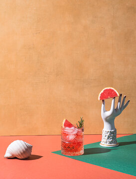 Red cocktail in base of Campari or bitter with blood red oranges (tarocco), surreal composition with ceramic vintage  women hand and sea shell. Aperitif with Americano or Negroni cocktail. Retro chic 