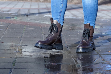 Women's traveler shoes tread on water on a concrete floor after heavy rain and icing.