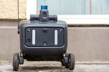A robot courier on wheels stands on the snow. Many cameras and sensors