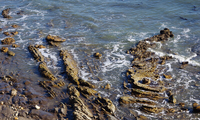 Pacific ocean stone and rock water edge in California after heavy winter storms washed the sand beach away