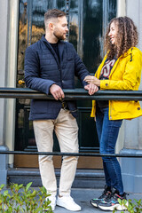 A young couple is standing on the porch in front of the entrance to the house