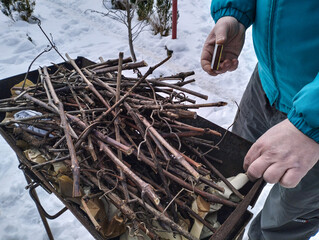 Man sets fire to wood with matches in a barbecu, grill. Camping. Winter in the village