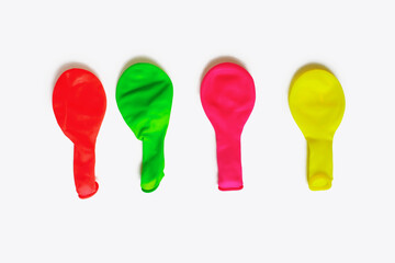Multicolored uninflated balloons on a white background. Balloons for decoration for the holidays in a deflated state. Four air latex balloons. Set of rubber balloons