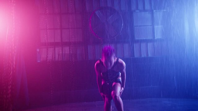 Sexy shot haired women with perfect body shape dancing in blue pink purple spotlights, moving passionately in darkness, go-go dance performance and peep show under pouring rain urban futuristic studio