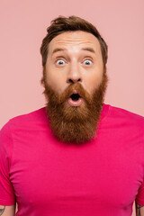 amazed bearded man with open mouth looking at camera isolated on pink.