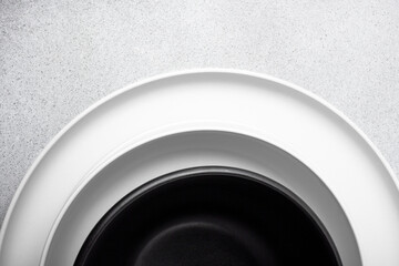Stack of white porcelain plates and black bowl on neutral gray background. copy space