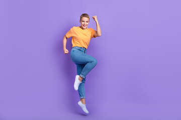 Fototapeta na wymiar Full size photo of satisfied girl wear sneakers t-shirt denim trousers scream yes clench fists isolated on purple color background