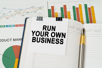 On the business charts is a notepad with the inscription - Run Your Own Business