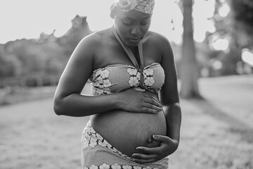 Pregnant african woman wearing tradtitional dress while touching belly outdoor