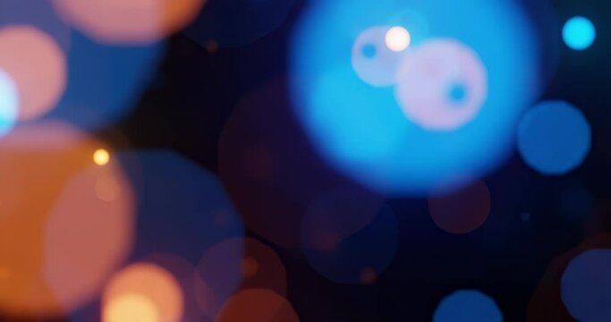 Beautiful orange and blue bokeh lights floating in the foreground, seamless loop animation