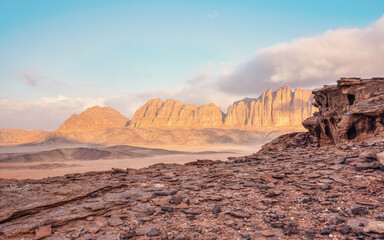 Red sandstone rocks formations in Wadi Rum (also known as Valley of the Moon) desert, Jordan. Morning sun shines to mountains background