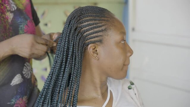 Young black woman braiding her hair outdoors