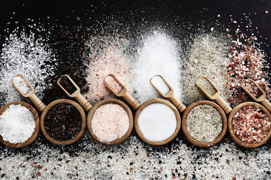 Colorful mix of salt varieties: sea and black, table and pink, himalayan and celtic. Food ingredients on dark background