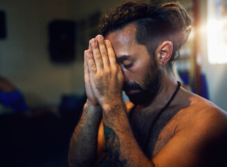 head shot portrait man mid adult yogi meditating praying with hands in namaste position indoors