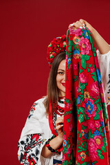 Portrait of ukrainian woman in traditional ethnic clothing and floral red wreath with handkerchief on viva magenta studio background. Ukrainian national embroidered dress call vyshyvanka