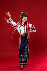 Portrait of ukrainian woman in traditional ethnic clothing and floral red wreath on viva magenta studio background. Ukrainian national embroidered dress call vyshyvanka. Pray for Ukraine