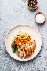 Braised vegetables with roasted chicken in ceramic plate, top view
