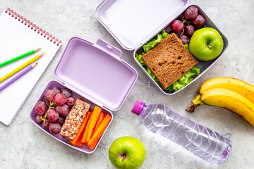 Student meal in purple lunch boxes filled with sandwich and fruits