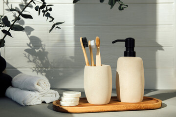 Stone bathroom accessories. Soap dispenser and a glass with wooden tooth counts on a light...