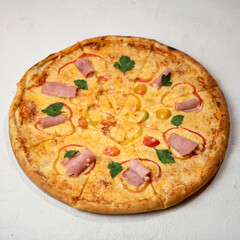Pizza with cheese, ham and pepper cut into pieces, decorated with parsley. Italian Cuisine. Isolate on white background. View from above. Copy space. 