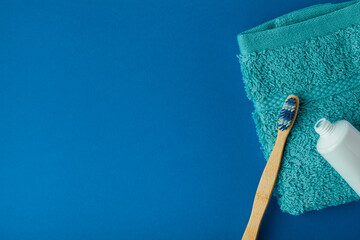 bamboo toothbrush on dark blue background with aqua towel and toothpaste