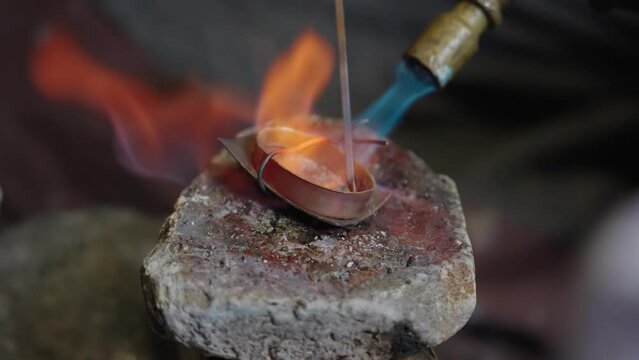 Craftsman soldering the tip of the scabbard in the workshop