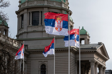 Serbian flags flutter in wind in front of National Assembly in Belgrade, symbol of Serbia