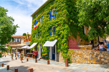 Ivy and plants cover the facade of medieval shops and cafes in the historic old town of Grimaud, France, in the Provence Cote d'Azur region.