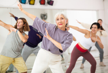 Group of adult people practices dance aerobics in class in the dance studio