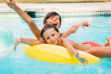 Two happy child having fun on summer pool. Boys playing at outdoor swimming pool