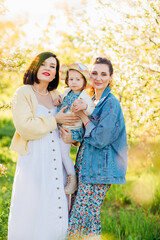 two attractive women with a little girl in their hands in a spring garden. 