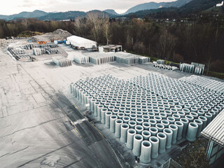 Aerial view at huge concrete pipes neatly stacked in rows at construction company base