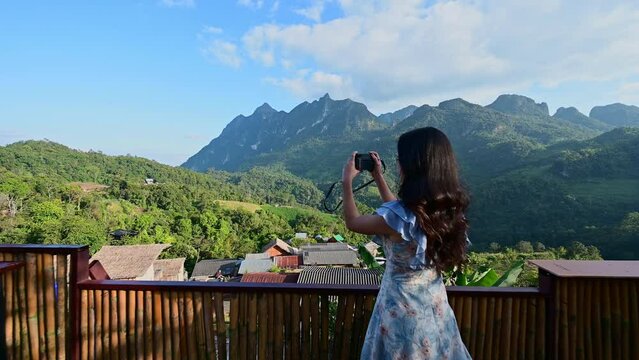 Asian woman at Doi Luang Chiang Dao view point, Chiang Mai, Thailand. And taking photos happily with the beautiful view