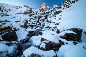 il monviso e la cascata di pian della regina, ghiacciata in una fredda alba d'inverno