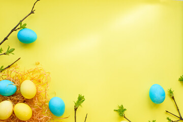 Naklejka na ściany i meble Easter spring holiday flatlay with nest, yellow eggs and blue eggs on yellow background. Easter concept. top view. copy space. flat lay