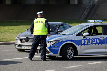 Policjant z lizakiem do zatrzymywania pojazdów kontroluje ruch drogowy - obrazy, fototapety, plakaty