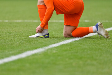 Obraz premium The football player itying his shoe on the turf of the pitch