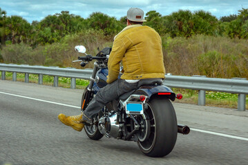 The biker rides forward, we see his back. In Florida.