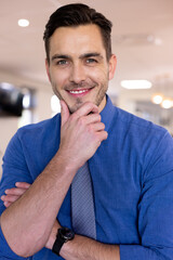 Portrait of happy caucasian businessman wearing blue shirt in modern office