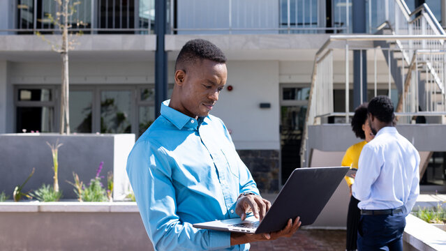 Happy diverse business people using laptop and talking in modern office