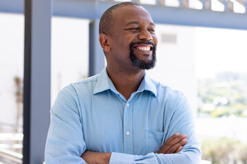 Happy african american businessman with arms crossed outside modern office