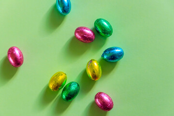 Easter chocolate eggs in foil on green background. Top view