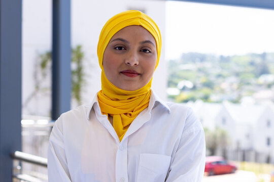 Portrait of happy biracial businesswoman with hijab in modern office