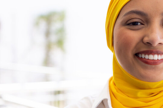 Portrait of happy biracial businesswoman with hijab in modern office