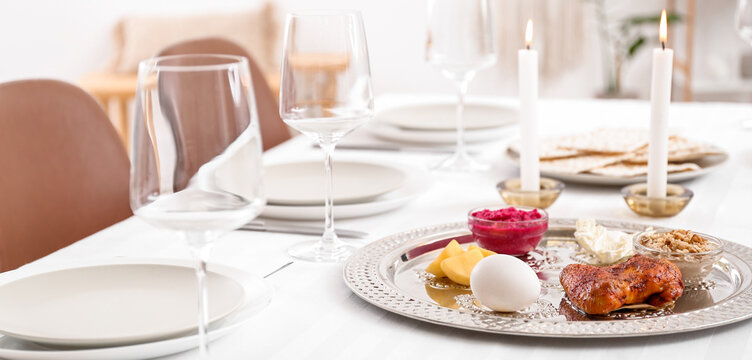 Passover Seder plate with traditional food on served table in dining room