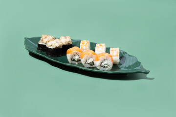 sushi on a plate in the shape of a banana leaf on a green background