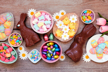 Easter candies. Above view table scene over a wood background. Chocolate bunnies, candy eggs and an assortment of sweets.