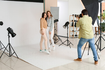 Male photographer taking picture of beautiful models in studio