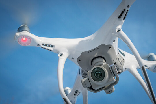 FORT COLLINS, CO, USA - DECEMBER 22, 2016:  DJI Phantom 4 pro quadcopter drone flying with a camera against blue sky.